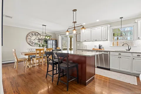 a kitchen with stainless steel appliances granite countertop a stove a sink dishwasher a dining table and chairs with wooden floor