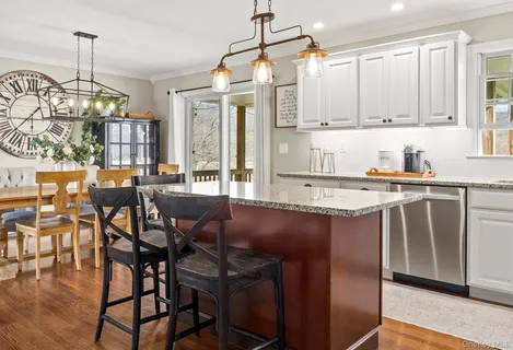 a kitchen with stainless steel appliances granite countertop a stove top oven a sink a dining table and chairs with wooden floor