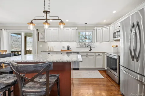 a kitchen with stainless steel appliances granite countertop a sink dishwasher a stove a refrigerator with a dining table and chairs