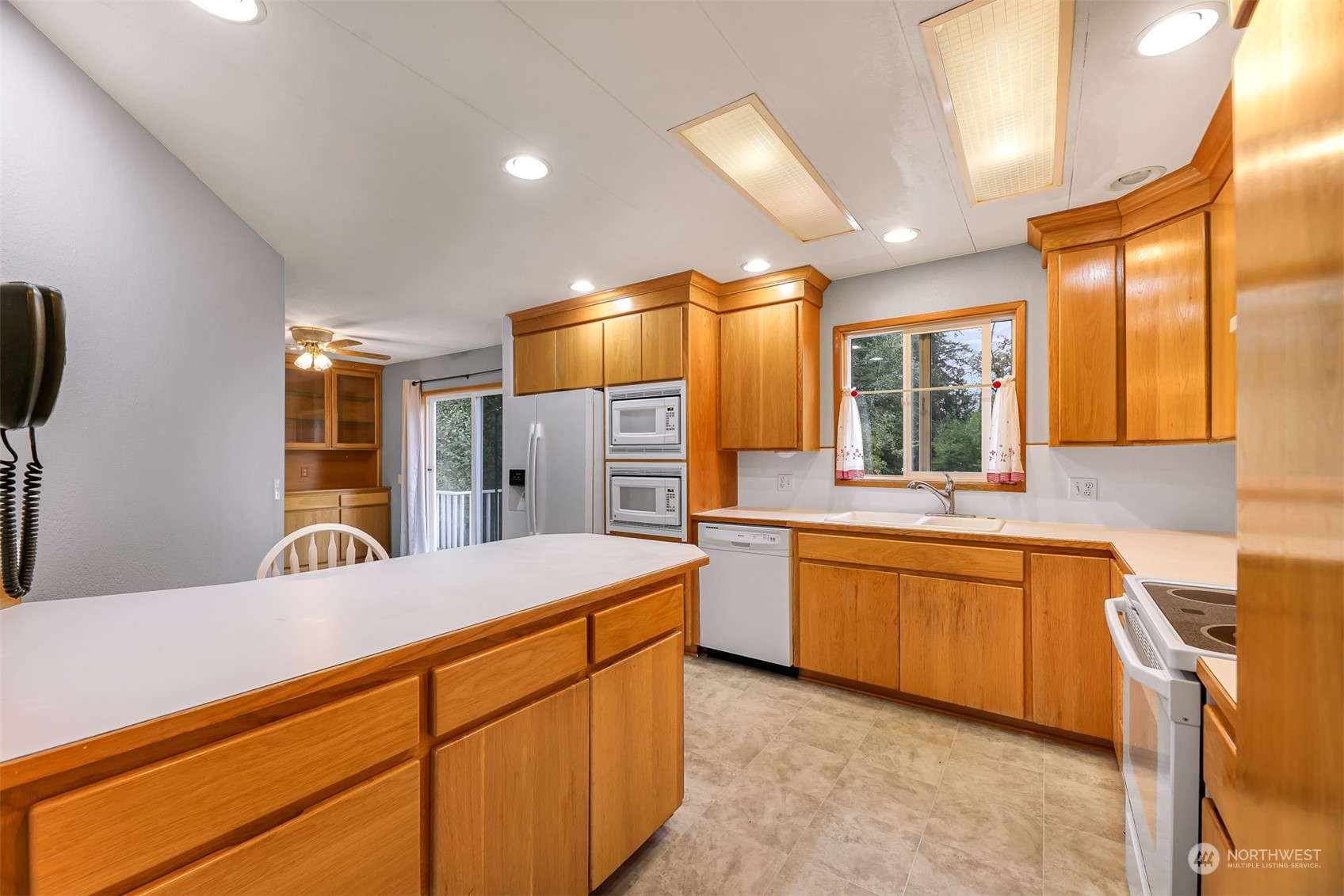 1182 East Axton Road Bellingham, WA 98226 - Photo 13 of 33 a kitchen with stainless steel appliances kitchen island granite countertop a sink and dishwasher a refrigerator with wooden cabinets