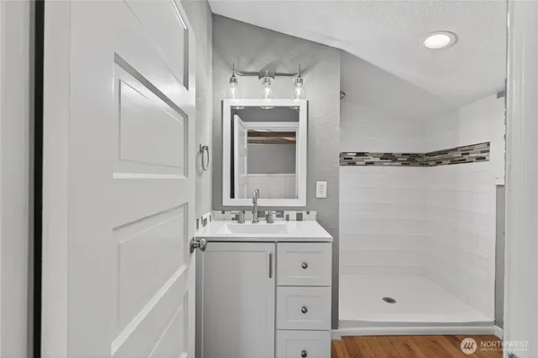 a bathroom with a shower sink vanity and mirror