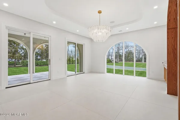 a view of an empty room with windows and chandelier