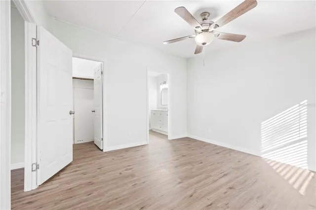 an empty room with wooden floor and ceiling fan
