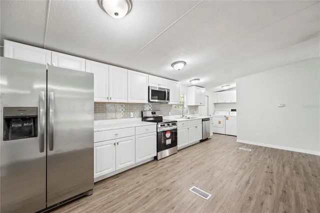 a large kitchen with cabinets wooden floor and stainless steel appliances