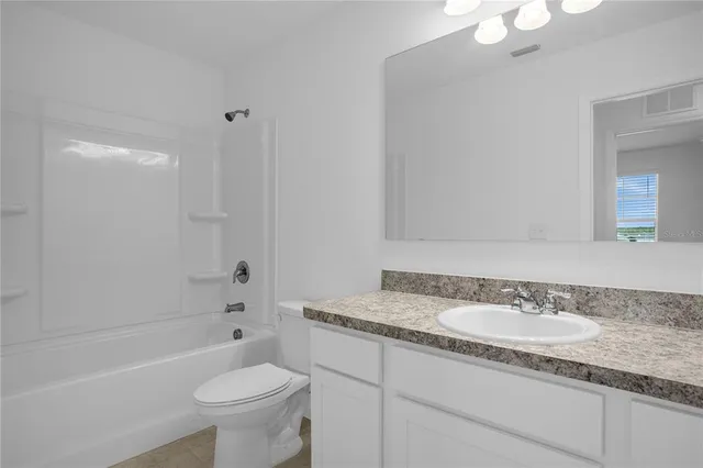 a bathroom with a granite countertop sink toilet mirror and bathtub