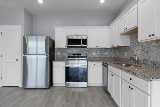 a kitchen with a refrigerator stove and white cabinets