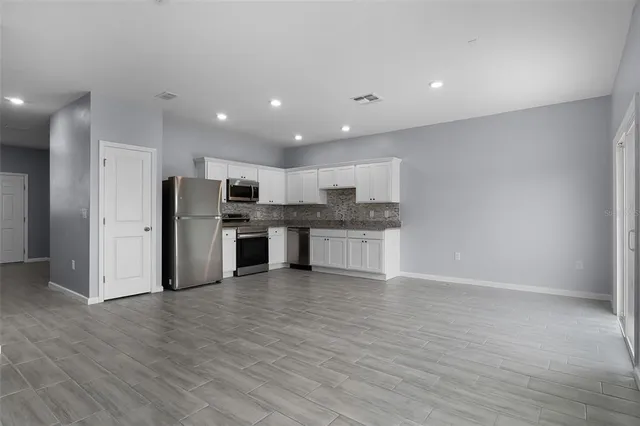 a large kitchen with stainless steel appliances kitchen island granite countertop a stove and a refrigerator