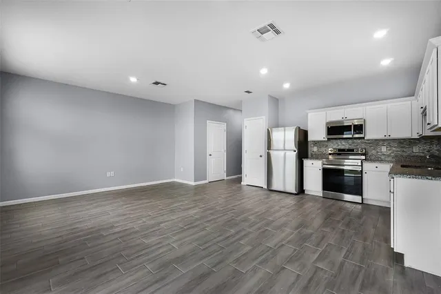 a view of kitchen with stainless steel appliances refrigerator stove microwave and cabinets