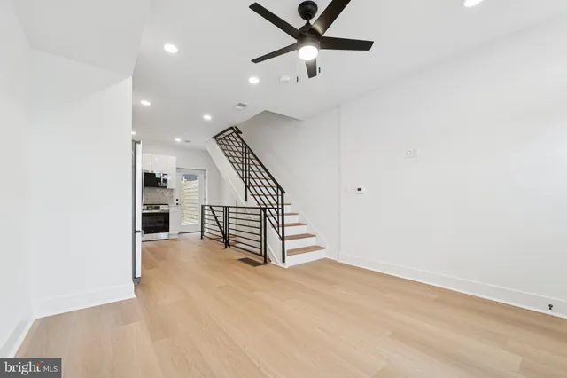 an empty room with wooden floor staircase and windows