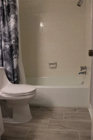 a white toilet sitting next to a bath tub