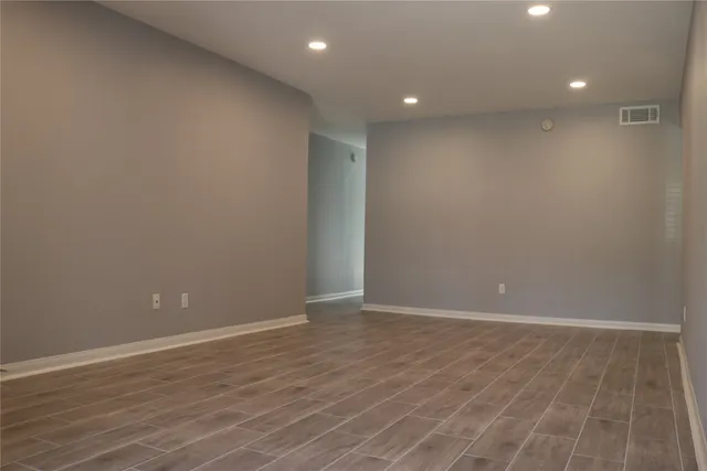 an empty room with wooden floor and entrance