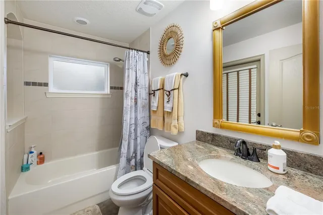 a bathroom with a granite countertop tub sink toilet and mirror