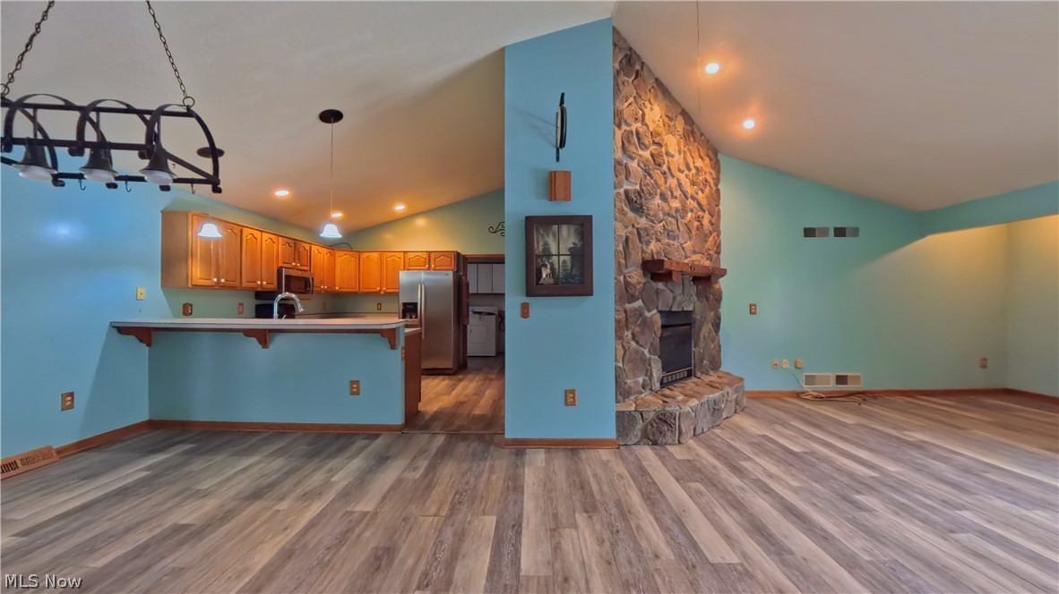48276 Dyke Road Negley, OH 44441 - Photo 7 of 30 Kitchen with lofted ceiling, a kitchen breakfast bar, stainless steel fridge, a stone fireplace, and light countertops