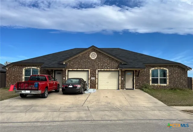 a front view of a house with cars parked