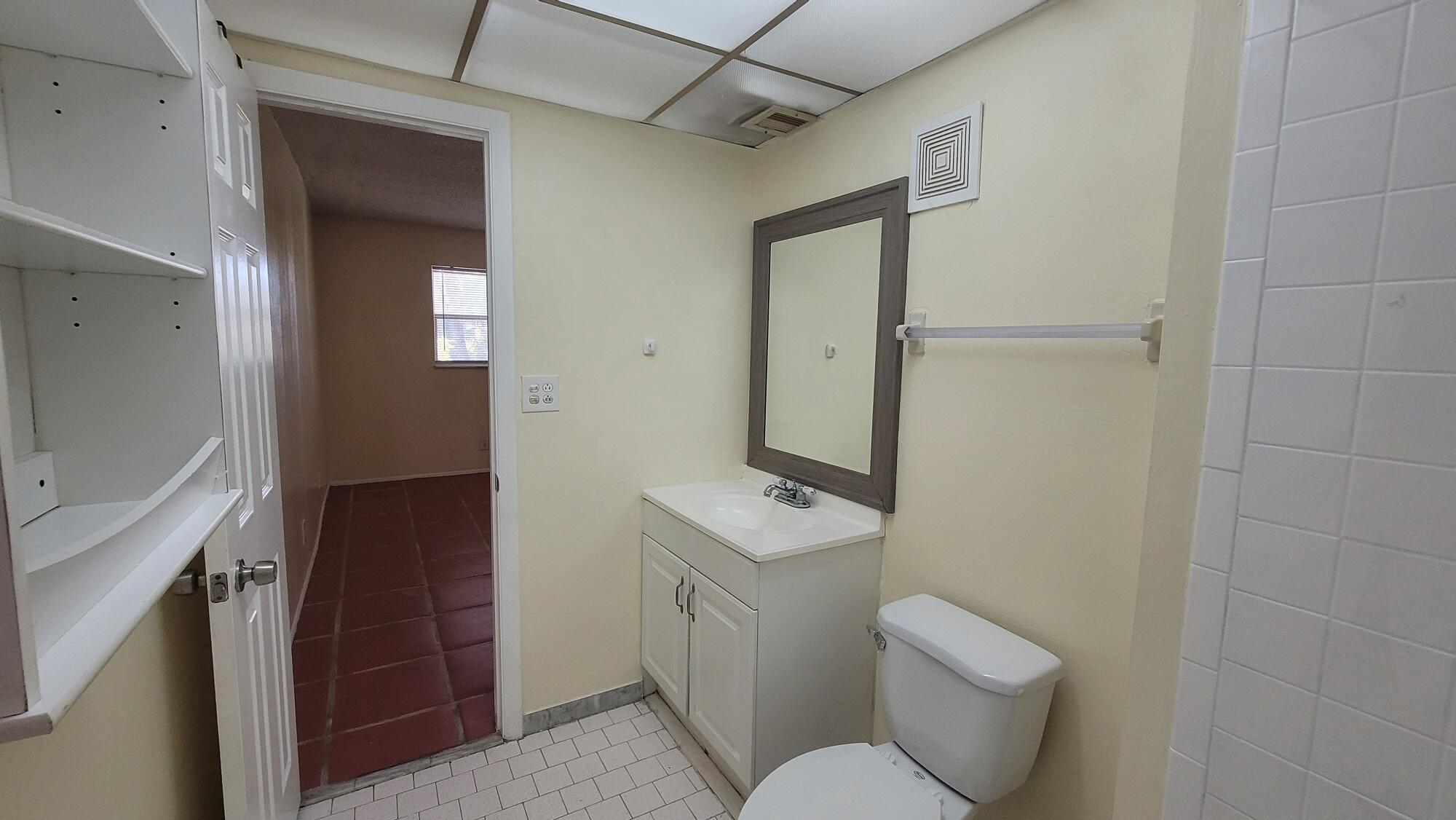 7911 North Colony Circle, Unit 305 Tamarac, FL 33321 - Photo 28 of 42 a bathroom with a toilet sink and mirror