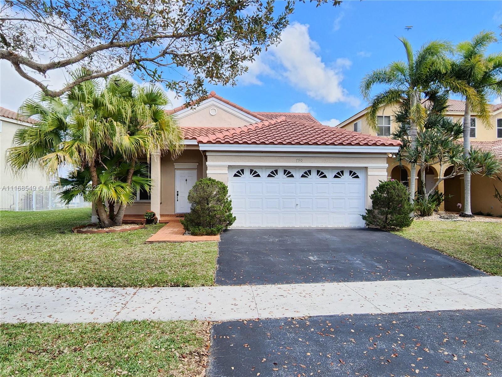 790 Falling Water Road Weston, FL 33326 - Photo 1 of 34 a front view of a house with a garden and a tree