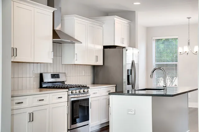 a kitchen with stainless steel appliances white cabinets and a refrigerator