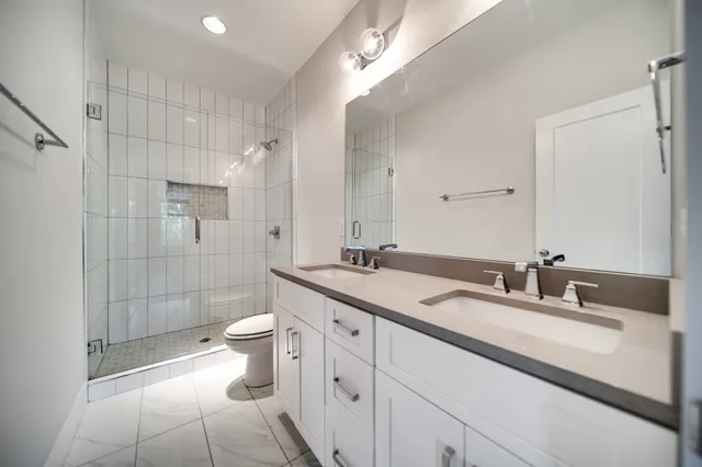 a bathroom with a double vanity sink toilet and shower