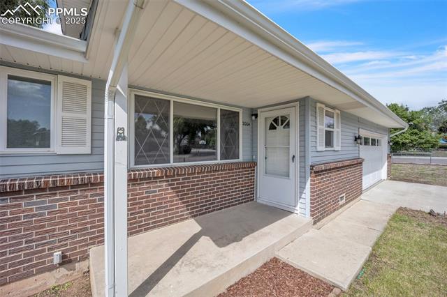 2004 Monterey Road Colorado Springs, CO 80910 - Photo 25 of 27 Doorway to property featuring brick siding, an attached garage, driveway, and crawl space