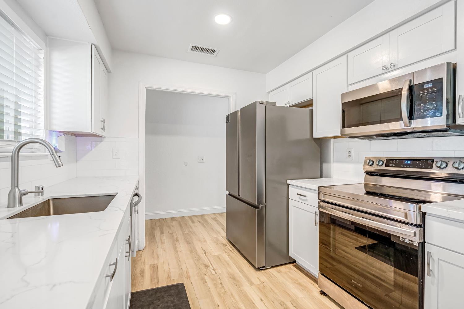 2428 West 3rd Street Madera, CA 93637 - Photo 19 of 39 a kitchen with stainless steel appliances a refrigerator microwave and sink