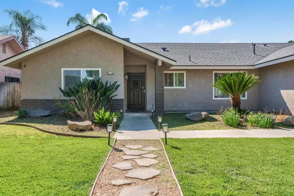 a front view of a house with a yard and potted plants