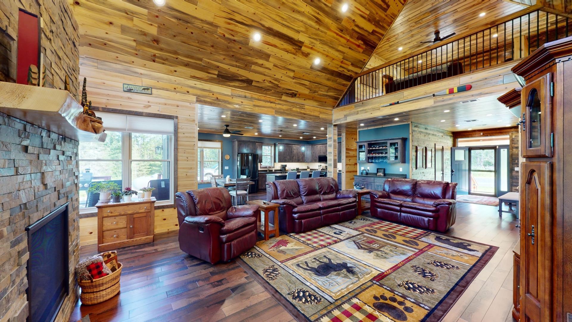 7523 Nelson Road Crane Lake, MN 55725 - Photo 17 of 50 Living room with high vaulted ceiling, a fireplace with raised hearth, dark wood-type flooring, and a ceiling fan