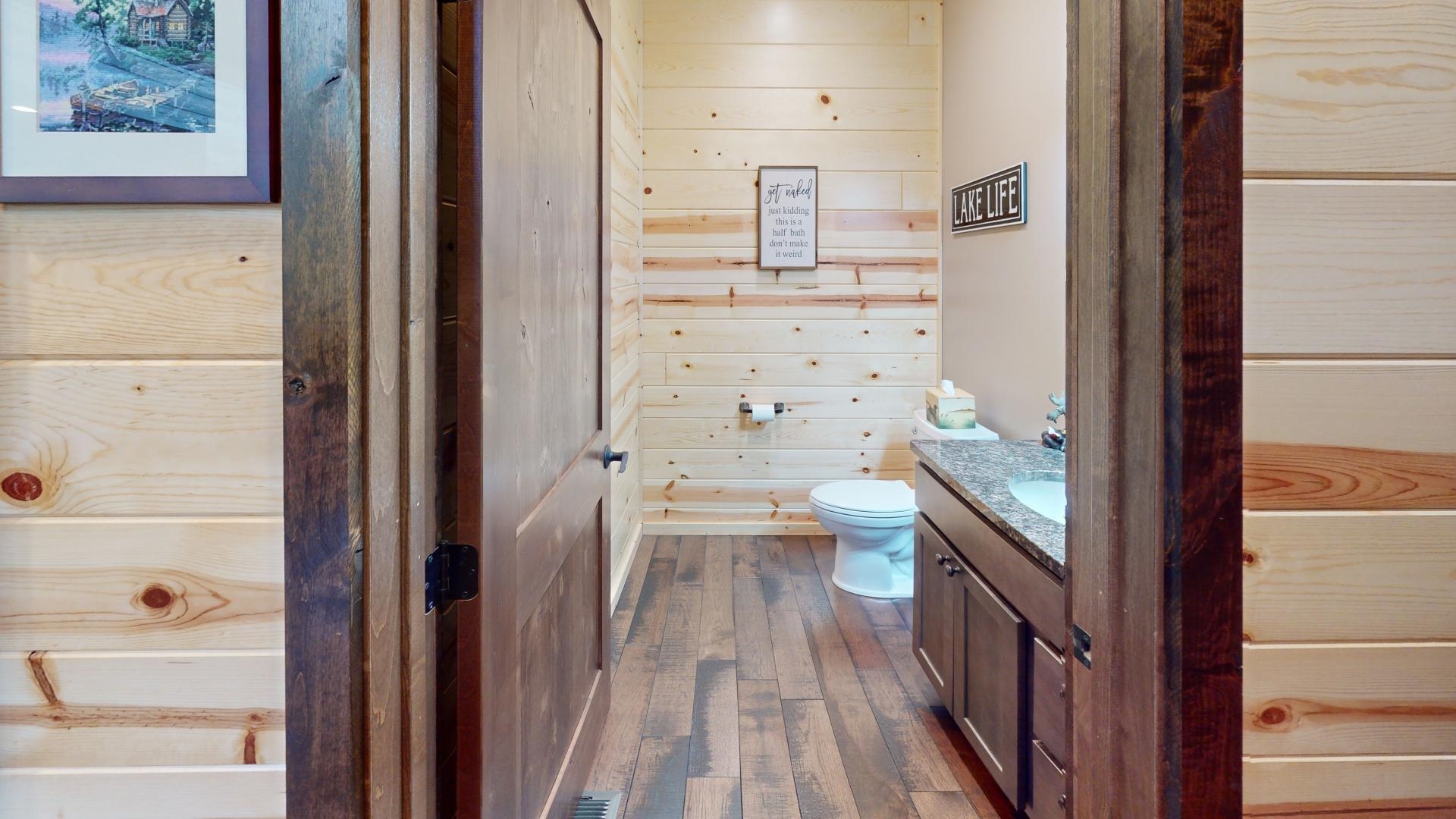 7523 Nelson Road Crane Lake, MN 55725 - Photo 24 of 50 Bathroom featuring wood walls, toilet, vanity, and hardwood / wood-style flooring