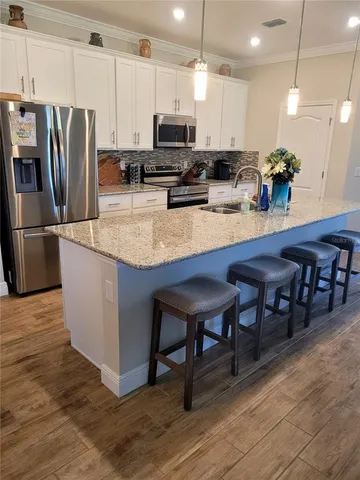 a kitchen with stainless steel appliances granite countertop a table chairs sink refrigerator and microwave