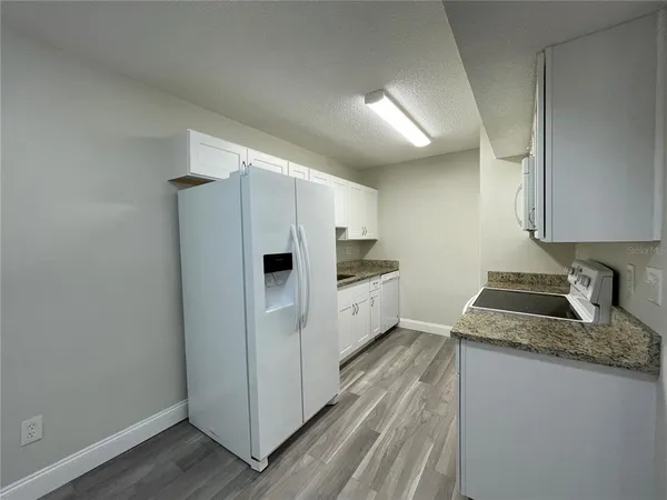 a kitchen with granite countertop cabinets and refrigerator
