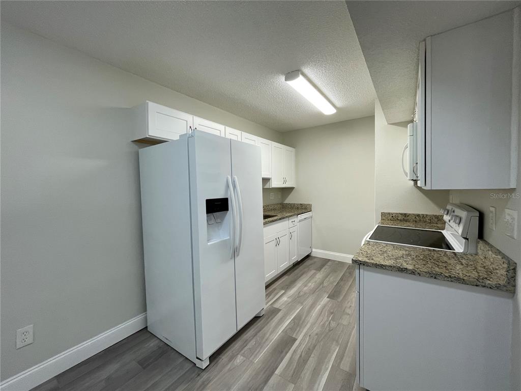 1600 Big Tree Road, Unit H3 South Daytona, FL 32119 - Photo 7 of 18 a kitchen with granite countertop cabinets and refrigerator