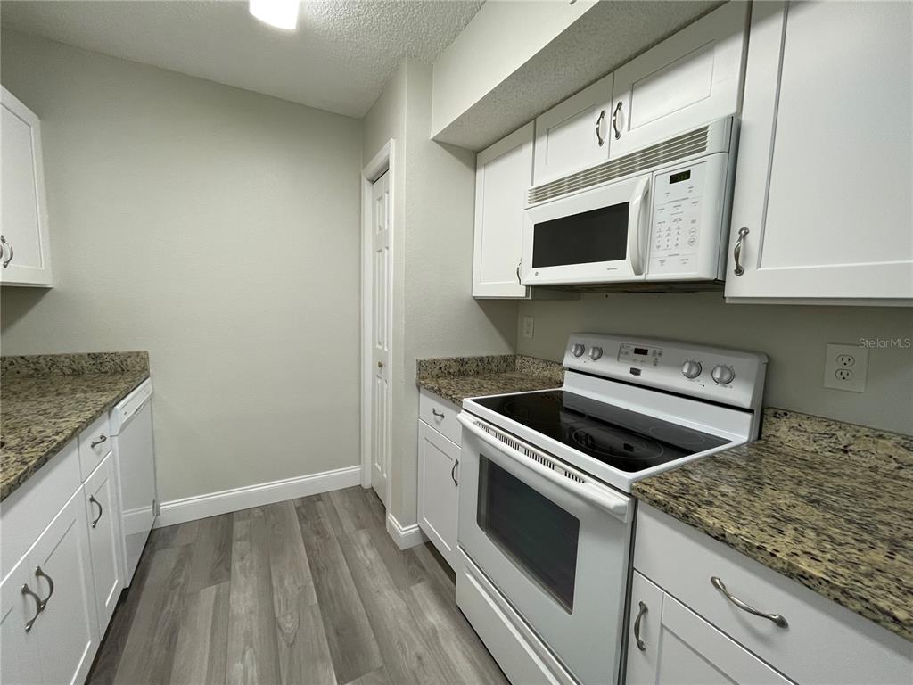 1600 Big Tree Road, Unit H3 South Daytona, FL 32119 - Photo 8 of 18 a kitchen with granite countertop wooden cabinets stove and sink