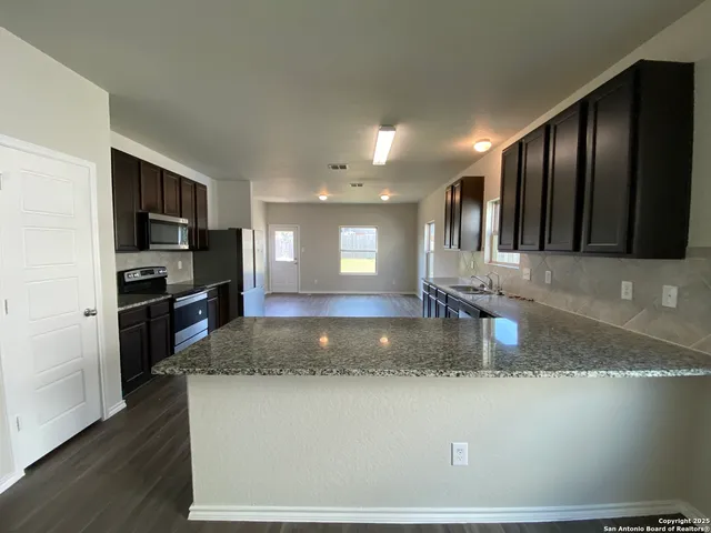 a kitchen with stainless steel appliances granite countertop a refrigerator a stove a sink a microwave and island