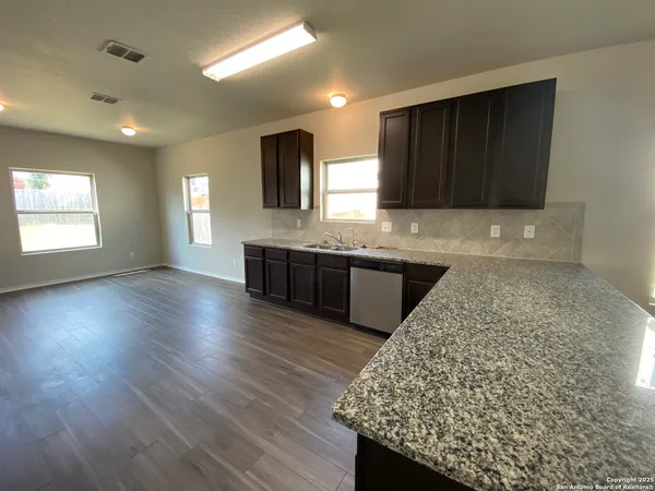 a kitchen with kitchen island granite countertop wooden cabinets a sink and dishwasher
