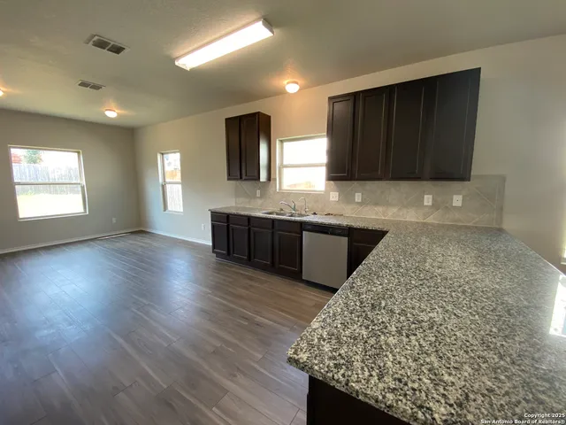 a kitchen with kitchen island granite countertop wooden cabinets a sink and dishwasher