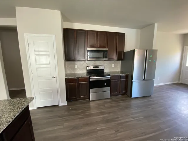 a kitchen with granite countertop a refrigerator and a stove top oven