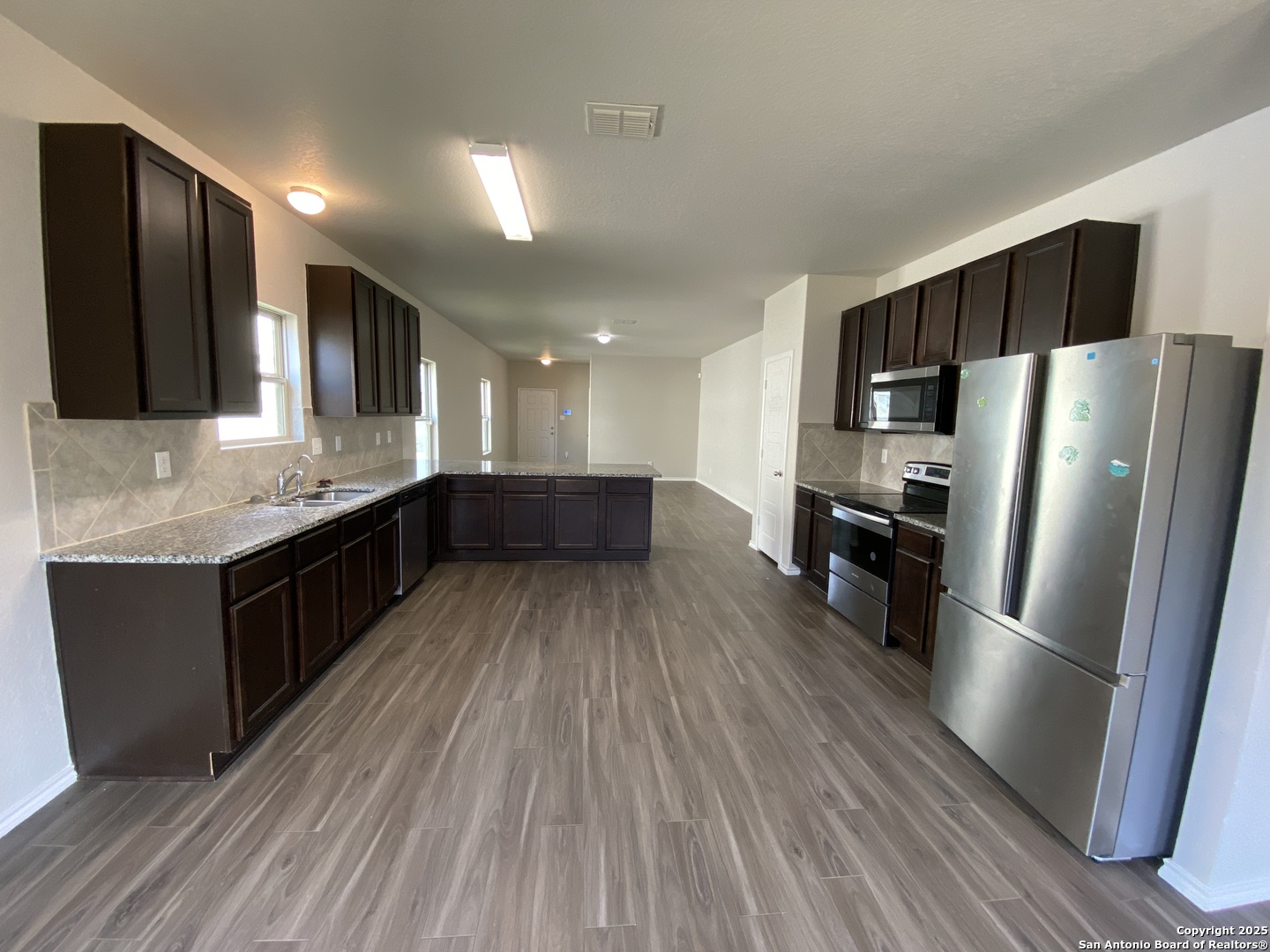 10822 Randolph Way Converse, TX 78109 - Photo 7 of 33 a kitchen with stainless steel appliances kitchen island granite countertop a refrigerator a sink dishwasher a stove and white countertops with wooden floor
