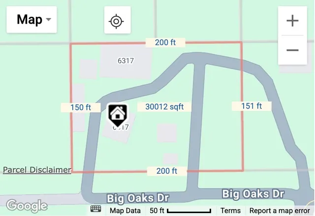 an aerial view of a house with a yard and large trees