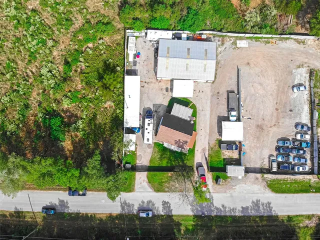 a view of a white house next to a yard and a large tree