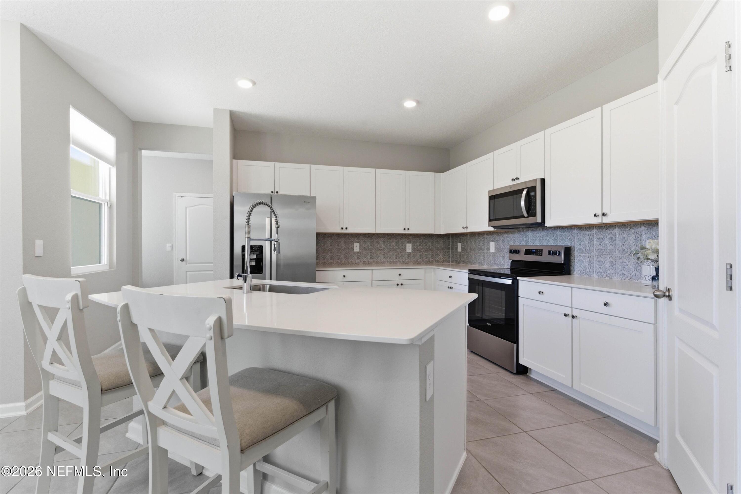 103 Seaport Breeze Road St. Augustine, FL 32095 - Photo 4 of 44 a kitchen with a sink white cabinets and stainless steel appliances
