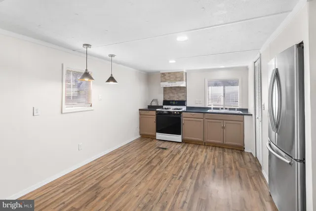 a kitchen with stainless steel appliances granite countertop a refrigerator a sink dishwasher a stove and white countertops with wooden floor