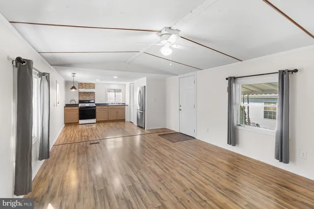 a view of a electric appliances in kitchen and empty room with wooden floor