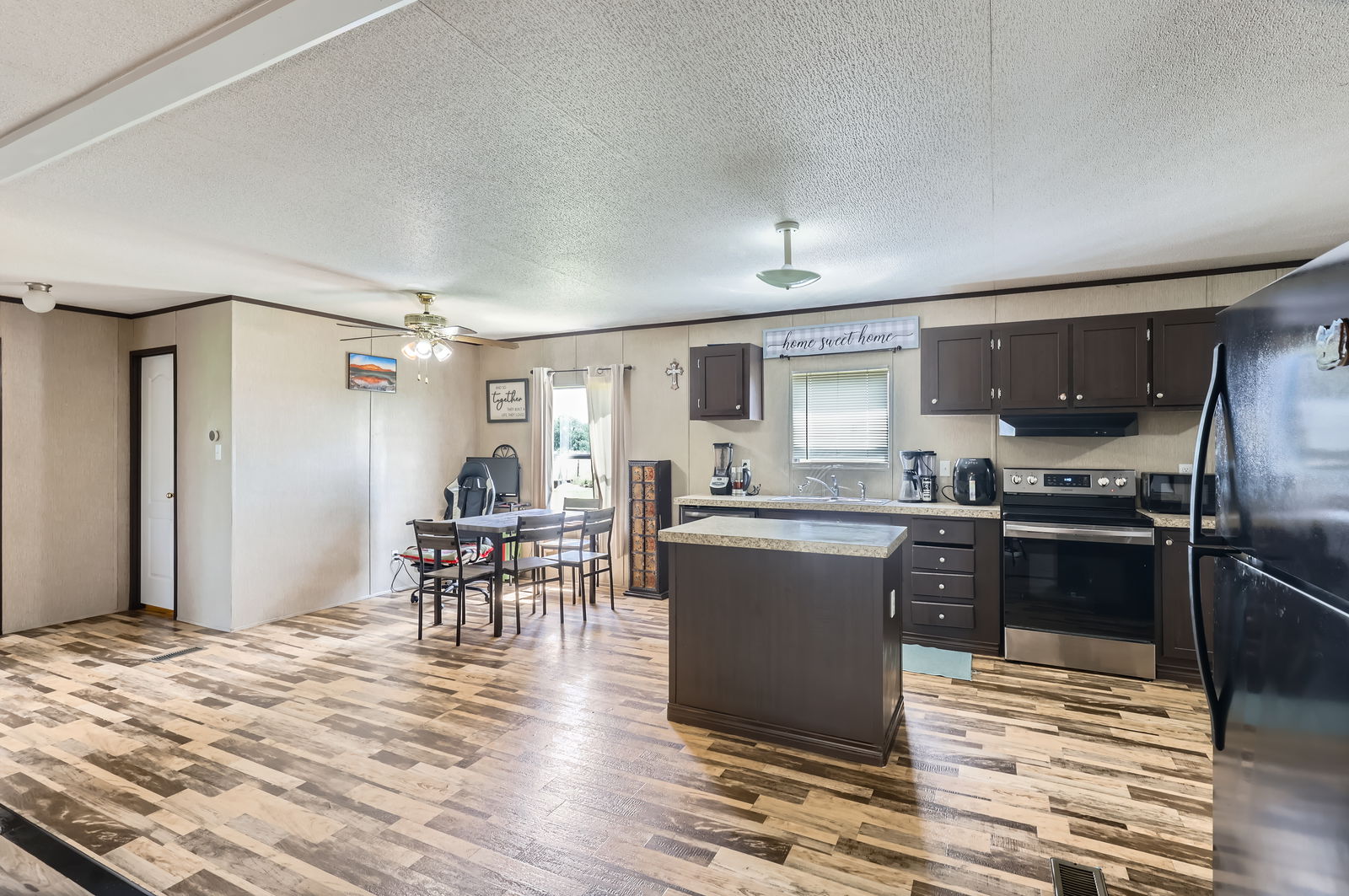 415 County Road 154 Georgetown, TX 78626 - Photo 17 of 28 Kitchen featuring stainless steel electric stove, freestanding refrigerator, light wood-style floors, a center island, and a textured ceiling