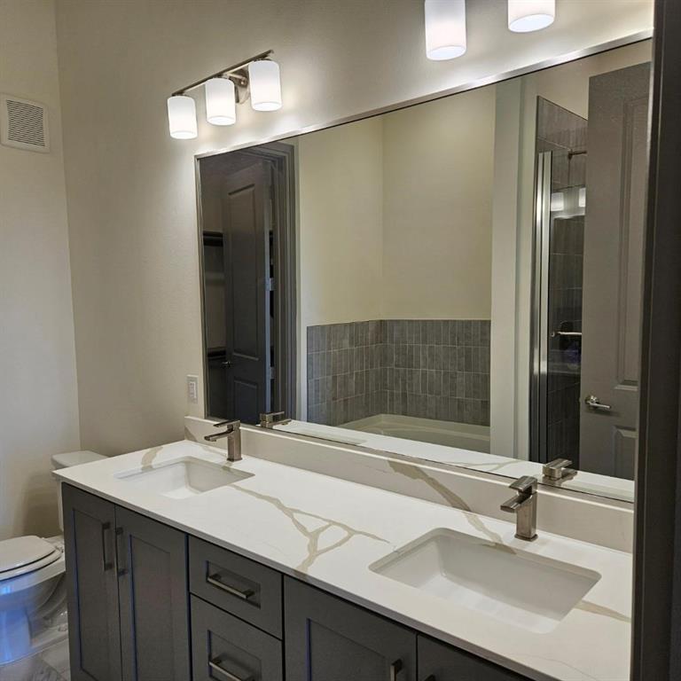 2700 Old Denton Road, Unit 2238 Carrollton, TX 75007 - Photo 16 of 21 Dual vanity with a white countertop featuring prominent veining, integrated rectangular sinks, and brushed nickel faucets