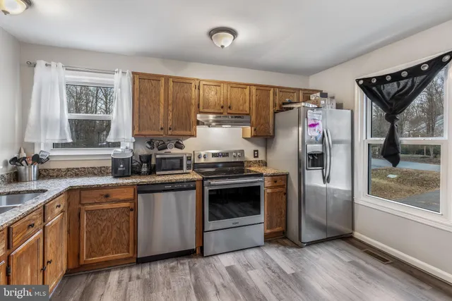 a kitchen with stainless steel appliances granite countertop a stove a sink and a refrigerator