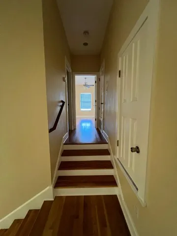 a view of staircase with wooden floor and white walls