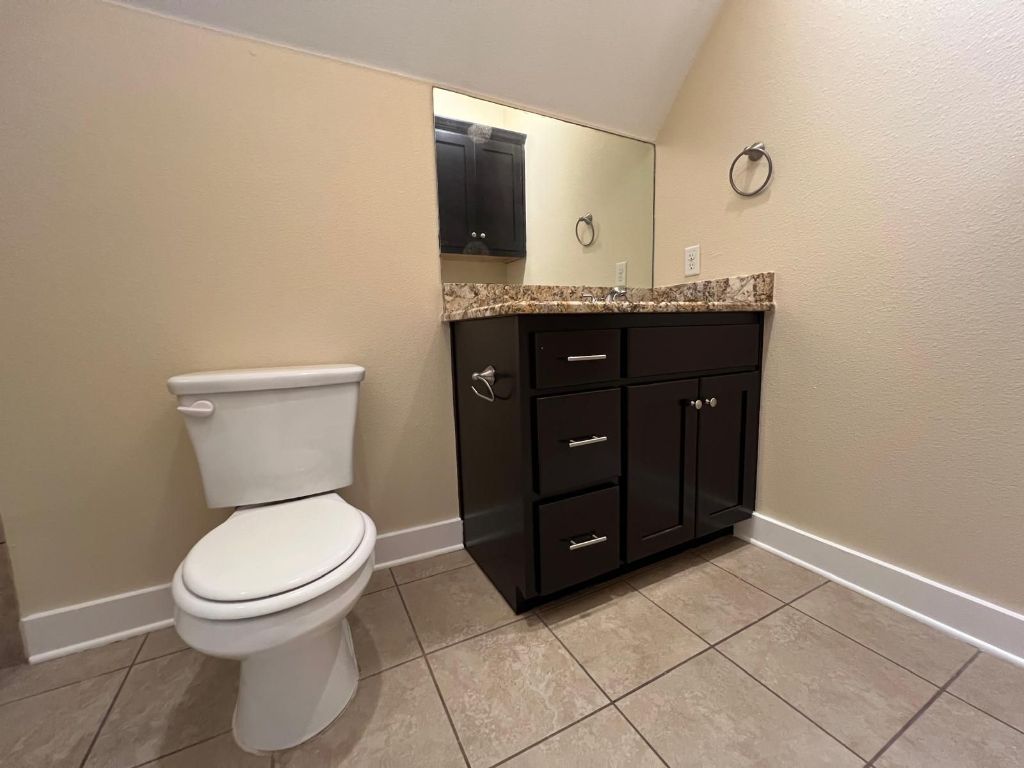 1309 Olander Street, Unit B Austin, TX 78702 - Photo 13 of 17 a bathroom with a granite countertop toilet sink and mirror
