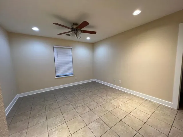 an empty room with a ceiling fan and window