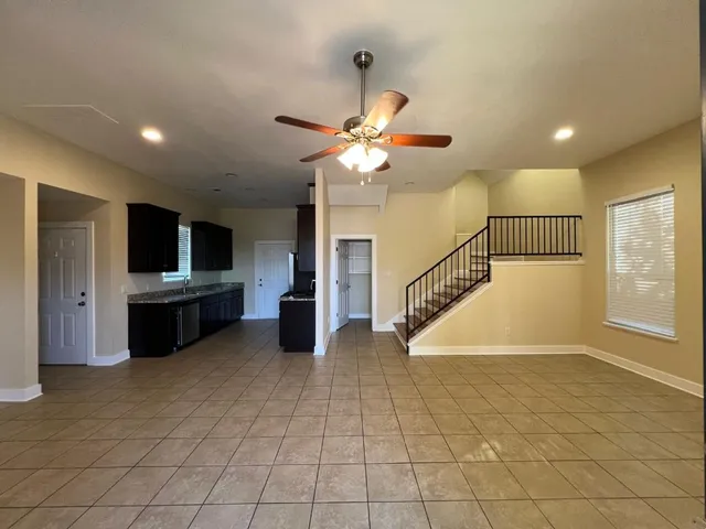 a view of an empty room with kitchen view and a window