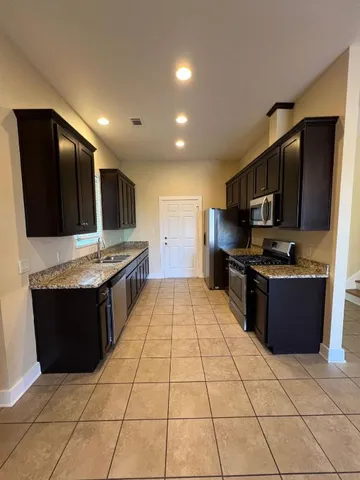 a kitchen with stainless steel appliances granite countertop a refrigerator and a stove