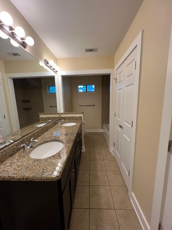 1309 Olander Street, Unit B Austin, TX 78702 - Photo 8 of 17 a bathroom with a granite countertop sink a mirror and a shower